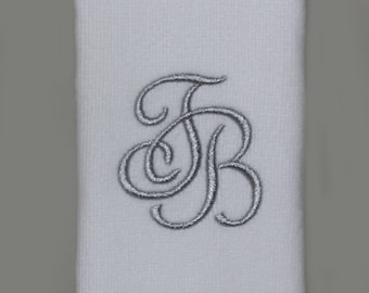 May include: White hand towel with a silver embroidered monogram of the letters "FB" in a script font.