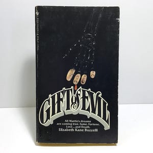 May include: Vintage paperback book titled "Gift of Evil" with a black cover. The cover features a skeletal hand with blood dripping from the fingertips. The title is in a stylized font, with the author's name and a tagline below.