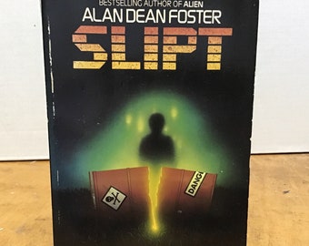 May include: A book cover with a black background and a green glow in the center. The title "SLIPT" is in large, yellow letters. The author's name, "ALAN DEAN FOSTER", is in white letters above the title. The book cover also features a skull and crossbones symbol and the text "SOMETHING STRANGE AND WONDERFUL IS HAPPENING DOWN AT THE CHEMICAL DUMP".