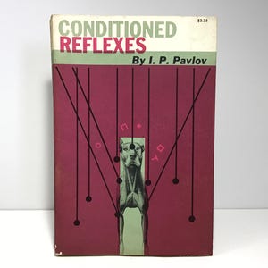 May include: A vintage book cover with a red background and black text. The title is "Conditioned Reflexes" by I. P. Pavlov. A black and white illustration of a dog is in the center of the cover.
