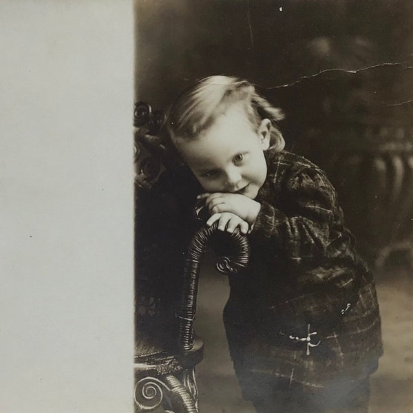 RPPC vintage d’enfant timide avec chaise - Antique Real Photo Carte postale c.1910s - Mignonne souriante jeune fille timide portant une robe à carreaux en tartan