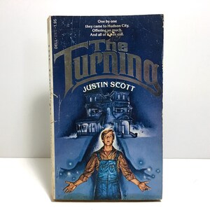 May include: A paperback book titled "The Turning" by Justin Scott. The cover features a blue background with a spooky house illustration and a young man in overalls. The text "One by one they came to Hudson City. Offering so much. And all of it was evil." is also visible.