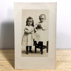 Antica cartolina con foto reali Giovane ragazza e ragazzo edoardiano, Ragazza con bambola, Ragazzo con palla, Bambini edoardiani in abiti bianchi, RPPC dei primi anni del 1900