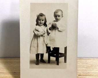 Carte postale ancienne avec photo réelle, jeune fille édouardienne et garçon, fille avec poupée, garçon avec ballon, tout-petits édouardiens en robes blanches, CPRP du début des années 1900
