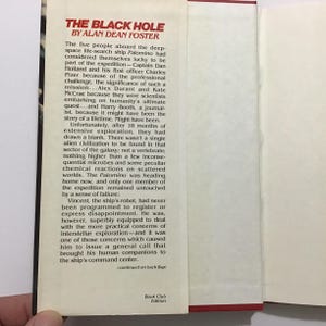 Op de afbeelding: Open boek met de titel "THE BLACK HOLE" van Alan Dean Foster. De tekst beschrijft een ruimtemissie. Het boek is een Boekenclub Editie.