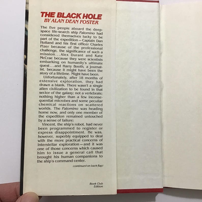 Op de afbeelding: Open boek met de titel "THE BLACK HOLE" van Alan Dean Foster. De tekst beschrijft een ruimtemissie. Het boek is een Boekenclub Editie.