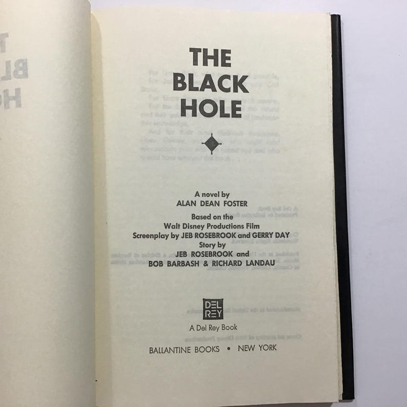 Op de afbeelding: Open boek met de titel "THE BLACK HOLE" in dikke zwarte letters. De naam van de auteur, Alan Dean Foster, staat eronder. Gebaseerd op de Walt Disney Productions Film. Uitgegeven door Ballantine Books, New York.
