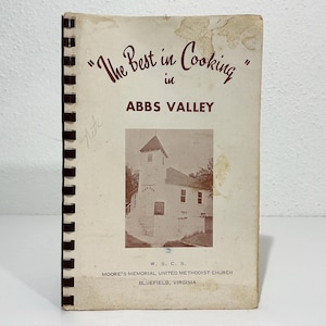 May include: A spiral-bound cookbook titled The Best in Cooking in ABBS VALLEY with a brown and white cover featuring a photograph of a church building. The text includes W. S. C. S. Moore's Memorial United Methodist Church, Bluefield, Virginia.