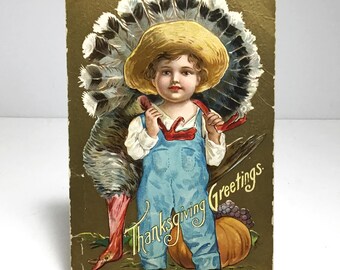 Postal antigua de "Saludos de Acción de Gracias" - Niño campesino rústico con un gran pavo y una calabaza - Tarjeta dorada original de la década de 1910 con relieve.