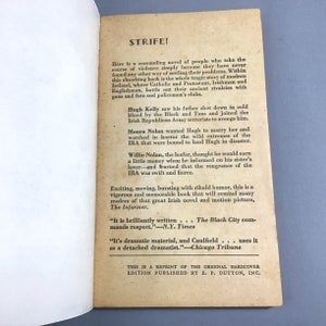 K&ouml;nnte beinhalten: Ein Vintage-Taschenbuchcover mit wei&szlig;em Hintergrund und schwarzem Text. Der Titel des Buches lautet "STRIFE!" und der Text beschreibt das Buch als einen "ersch&uuml;tternden Roman" &uuml;ber die Irische Republikanische Armee. Das Buch ist ein Nachdruck der urspr&uuml;nglichen Hardcover-Ausgabe, die von E.P. Dutton, Inc. ver&ouml;ffentlicht wurde.