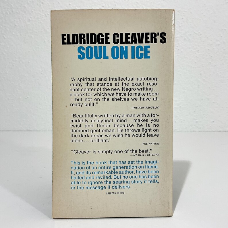 Puede incluir: La contraportada del libro Soul on Ice de Eldridge Cleaver, con texto en negro y azul sobre un fondo crema. Incluye rese&ntilde;as impresas de The New Republic, The Nation y Maxwell Geismar, junto con el texto Printed in USA.