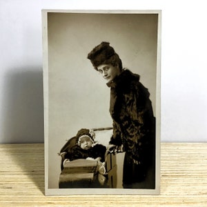 Antike echte Fotopostkarte, Edwardianische Mutter und Baby in passenden Winterpelzmänteln, Mutter mit Kind im Kinderwagen, Sepia RPPC aus den frühen 1900er Jahren