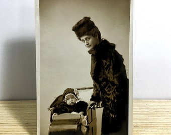 Carte postale ancienne avec photo réelle, mère édouardienne et bébé dans des manteaux de fourrure d'hiver assortis, mère avec enfant dans une poussette, sépia RPPC du début des années 1900