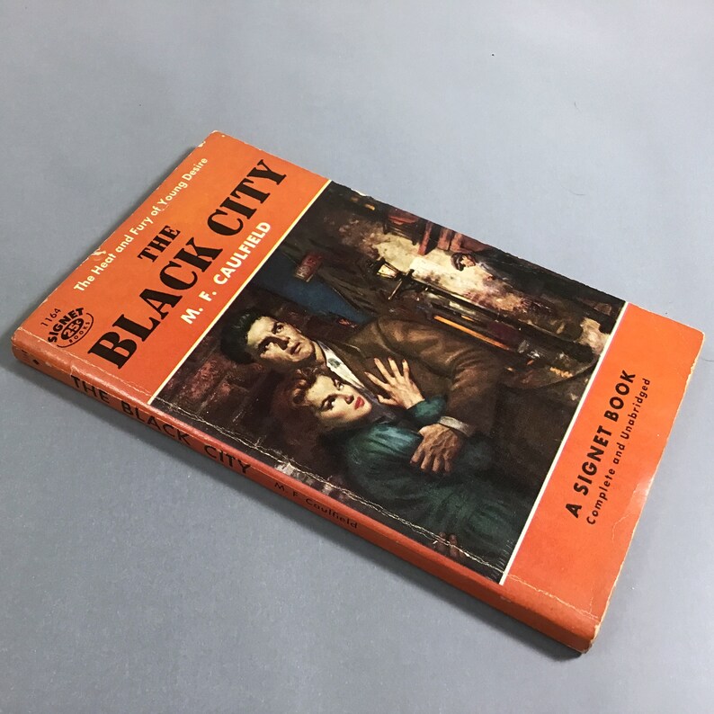 K&ouml;nnte beinhalten: Ein Vintage-Taschenbuch mit dem Titel "The Black City" von M.F. Caulfield. Das Cover zeigt eine dramatische Illustration eines Mannes und einer Frau in einem schwach beleuchteten Raum. Das Buch ist ein Signet Book, vollst&auml;ndig und ungek&uuml;rzt.