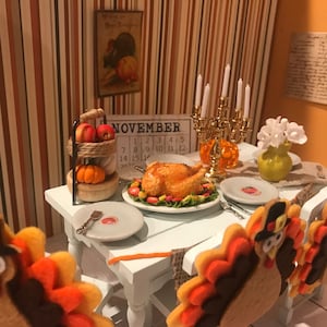 May include: A miniature Thanksgiving table setting with a roasted turkey, a calendar showing the month of November, a tiered stand with apples and a pumpkin, a gold candelabra with lit candles, a yellow vase with white flowers, and a plate with a turkey cookie on each chair.