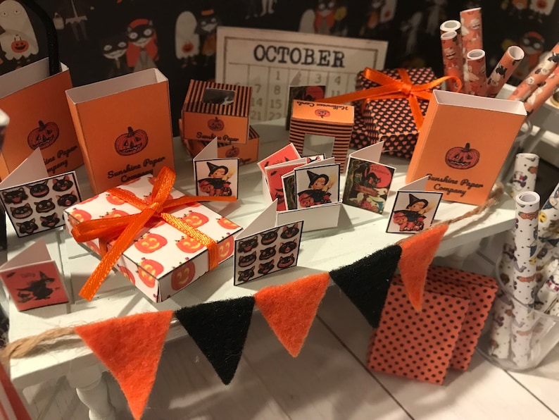 Puede incluir: Un kit de manualidades en miniatura con tem&aacute;tica de Halloween con art&iacute;culos de papel naranja y negro. El kit incluye cajas, tarjetas y papel de regalo con dise&ntilde;os de calabazas y gatos. El kit tambi&eacute;n incluye un calendario con la palabra "OCTUBRE" impresa en &eacute;l.