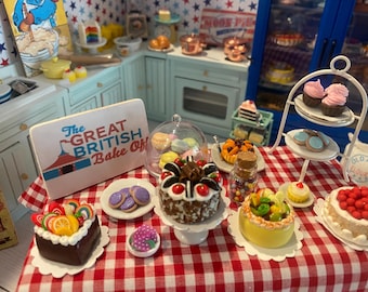 May include: Miniature kitchen scene with a red and white checkered tablecloth, featuring various cakes, cookies, and sweets. A sign reads "The Great British Bake Off." A tiered serving stand holds cupcakes and cookies. Other desserts include a cake with red berries.