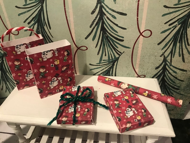 Puede incluir: Dos bolsas de regalo rojas y blancas con un dise&ntilde;o navide&ntilde;o de Peanuts y una caja de regalo roja y blanca con un dise&ntilde;o navide&ntilde;o de Peanuts y un rollo de papel de regalo rojo y blanco con un dise&ntilde;o navide&ntilde;o de Peanuts.