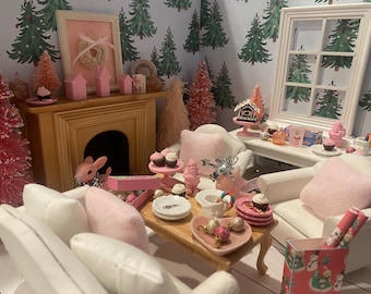 May include: Miniature Christmas-themed room with a fireplace, furniture, and decorations. Pink and white accents are used throughout the scene, including cupcakes, ornaments, and a framed wreath. The wallpaper features a repeating pattern of green Christmas trees.