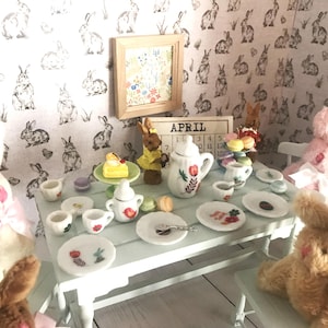 May include: A miniature Easter tea party scene with bunny plush toys, a small table set with tiny plates, cups, and a teapot. The background features a rabbit-themed wallpaper and a framed picture. The scene evokes a whimsical, springtime atmosphere.