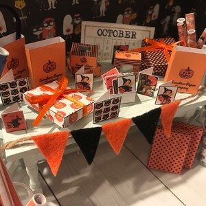 Puede incluir: Un escaparate en miniatura con tem&aacute;tica de Halloween con decoraciones naranjas y negras. La tienda ofrece una variedad de art&iacute;culos, incluyendo cajas de regalo, papel de regalo y tarjetas. La tienda est&aacute; decorada con una pancarta que dice "OCTUBRE" y un calendario con el mes de octubre resaltado.