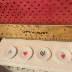 Puede incluir: Cuatro peque&ntilde;os platos de cer&aacute;mica blanca con diferentes dise&ntilde;os. Un plato tiene un unicornio, uno tiene un coraz&oacute;n, uno dice "Te amo" con un coraz&oacute;n y uno tiene un p&aacute;jaro con un coraz&oacute;n.