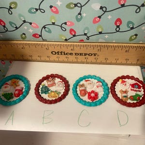May include: Four Christmas-themed bottle caps with red and blue trim. Each cap features a different holiday scene with Santa Claus, reindeer, and other festive elements. The caps are labeled A, B, C, and D.