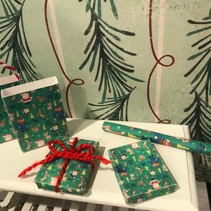 Puede incluir: Tres peque&ntilde;as bolsas de regalo y dos regalos envueltos con un patr&oacute;n navide&ntilde;o verde y rojo. Las bolsas tienen un asa blanca y un asa a rayas roja y blanca. Los regalos est&aacute;n atados con una cuerda roja.