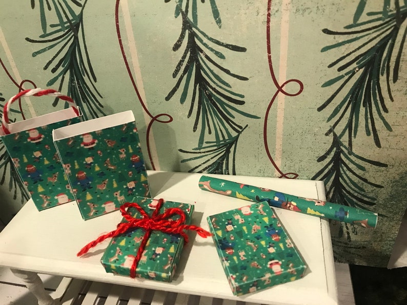 Puede incluir: Tres peque&ntilde;as bolsas de regalo y dos regalos envueltos con un patr&oacute;n navide&ntilde;o verde y rojo. Las bolsas tienen un asa blanca y un asa a rayas roja y blanca. Los regalos est&aacute;n atados con una cuerda roja.