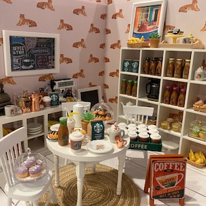 May include: A detailed miniature coffee shop setting, featuring a white table, chairs, and shelves stocked with coffee products. There's a cash register, coffee machine, and a sign reading "Coffee Fresh Brewed Best in Town". The walls are adorned with a tiger print.