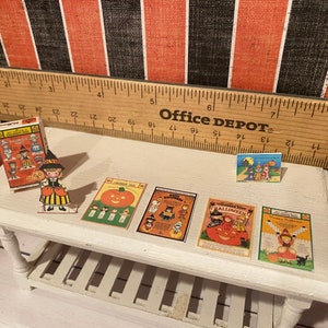 May include: A collection of vintage Halloween paper dolls and cards. The dolls are dressed in costumes and the cards feature images of pumpkins, ghosts, and witches. The cards have the text "Happy Halloween" and "Trick or Treat".