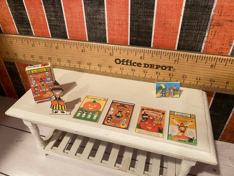 May include: A collection of vintage Halloween paper dolls and cards. The dolls are dressed in costumes and the cards feature images of pumpkins, ghosts, and witches. The cards have the text "Happy Halloween" and "Trick or Treat".