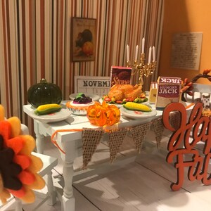 May include: A miniature Thanksgiving dinner scene with a felt turkey, a table set with a roasted turkey, pie, corn, and a pumpkin. A banner reads "Happy Fall". The scene includes a calendar showing November.