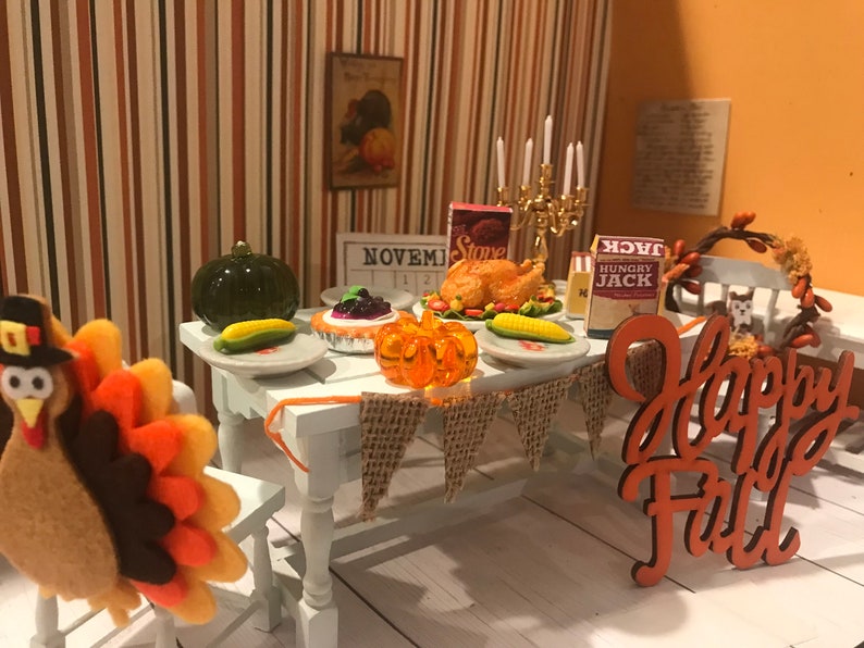 May include: A miniature Thanksgiving dinner scene with a felt turkey, a table set with a roasted turkey, pie, corn, and a pumpkin. A banner reads "Happy Fall". The scene includes a calendar showing November.