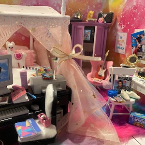Könnte beinhalten: Ein Miniatur-Puppenhaus-Schlafzimmer mit einem rosa Himmelbett, einem Computertisch mit Monitor, Tastatur und Drucker, einem Schminktisch mit Spiegel und Make-up sowie einem rosa-weißen Teppich. Das Zimmer ist mit Sternen und anderen mädchenhaften Details dekoriert.