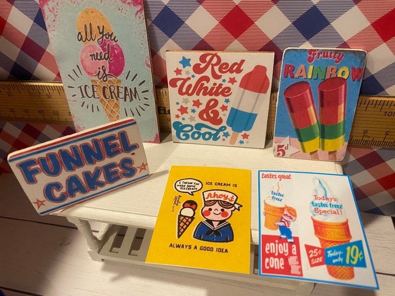 May include: A collection of vintage-style ice cream and dessert-themed signs. The signs feature phrases like "Funnel Cakes," "Red White & Cool," and "All you need is Ice Cream." The color palette includes red, white, blue, yellow, and pastel tones.
