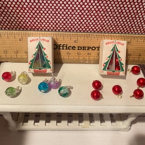 May include: Miniature Christmas ornaments and boxes with "HOLLY JOLLY" text. The ornaments are red, green, blue, and purple. The boxes have a Christmas tree design.