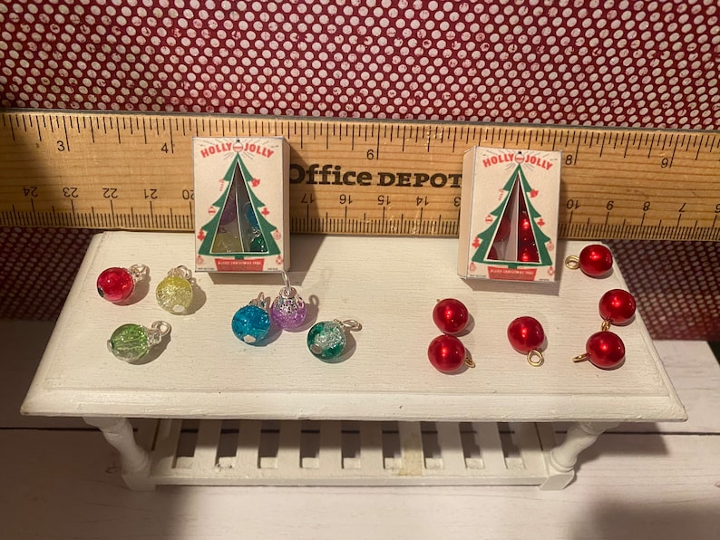 May include: Miniature Christmas ornaments and boxes with "HOLLY JOLLY" text. The ornaments are red, green, blue, and purple. The boxes have a Christmas tree design.