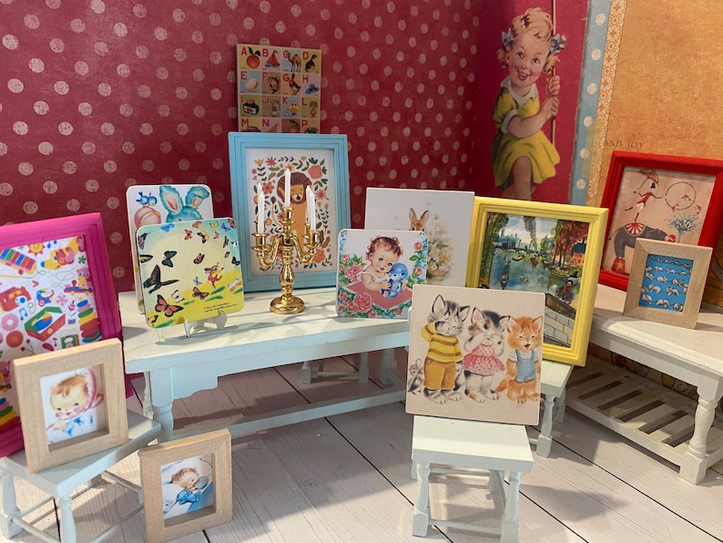 Puede incluir: Una colecci&oacute;n de impresiones art&iacute;sticas enmarcadas de estilo vintage, que incluyen un beb&eacute;, gatitos y una escena de canal. Los marcos son de varios colores, y tambi&eacute;n hay un candelabro dorado. El fondo es una pared rosa con lunares.