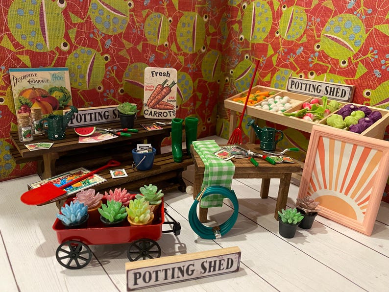 May include: A miniature potting shed scene featuring a red wagon with succulents, a wooden table with gardening tools, and a sign that reads "Potting Shed". The background has a red and green patterned wallpaper.