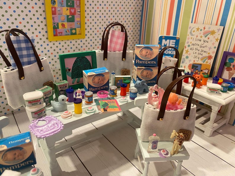 May include: Miniature scene featuring baby care products, including Pampers boxes, baby food jars, and a bib. Several tote bags with brown handles are present, along with small toys and decorative items. The scene is set on a white table and a small stool.
