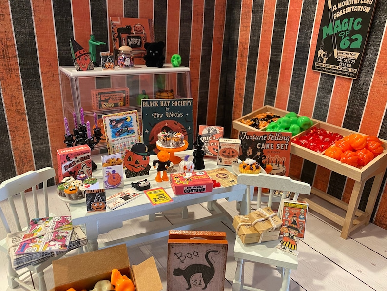 May include: A miniature Halloween shop with a white table and chairs, a display case with candles and a black cat, a wooden stand with orange and red candy, and various Halloween-themed decorations, including a sign that reads "Black Hat Society Fine Witches" and a sign that reads "Fortune Telling Cake Set".