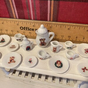 Puede incluir: Juego de t&eacute; navide&ntilde;o en miniatura con acabado blanco. El juego incluye una tetera, una jarra de crema, un azucarero, tazas y platillos. Cada pieza est&aacute; decorada con dise&ntilde;os festivos navide&ntilde;os, incluyendo osos de peluche, &aacute;rboles de Navidad y coronas.