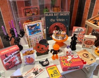 May include: A miniature Halloween scene with a black candlestick, a calendar, a sign that reads "Black Hat Society for Fine Witches", a box of "Trick or Treat" candy, and a variety of Halloween-themed decorations.
