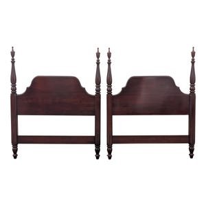May include: A pair of dark brown wooden headboards featuring tall, slender posts with decorative finials at the top. Each headboard has a smooth, arched central panel supported by two vertical posts and a horizontal base rail, showcasing a polished finish.