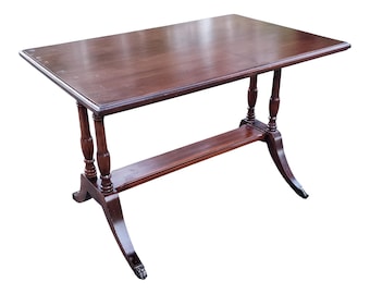 May include: A dark brown wooden table with a rectangular top and turned legs. The table has a lower shelf and a simple design.