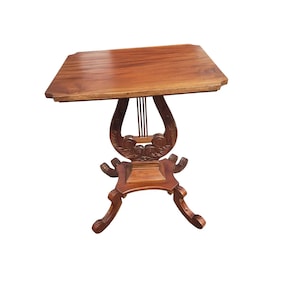 Puede incluir: Una mesa auxiliar de madera con una tapa cuadrada y una base en forma de lira. La mesa está hecha de madera oscura y tiene un acabado natural.