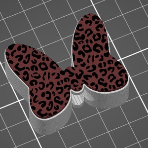 Könnte beinhalten: Ein 3D-gedruckter Schmetterling mit einem braunen und schwarzen Leopardenmuster.