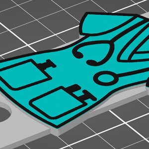 May include: A teal blue medical scrubs keychain with black outlines. The keychain features a stethoscope, two pockets, and a small medical symbol.