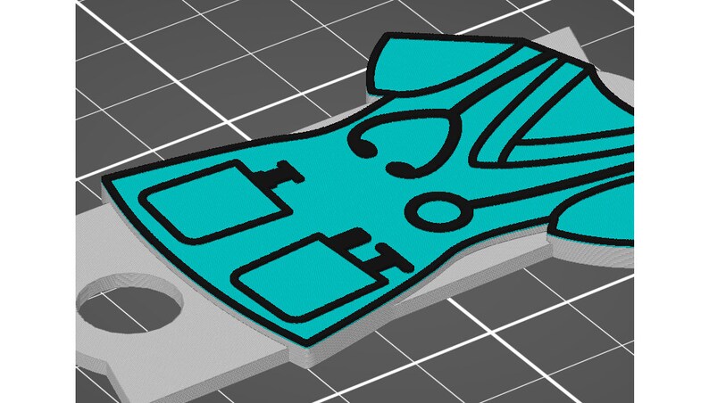 May include: A teal blue medical scrubs keychain with black outlines. The keychain features a stethoscope, two pockets, and a small medical symbol.